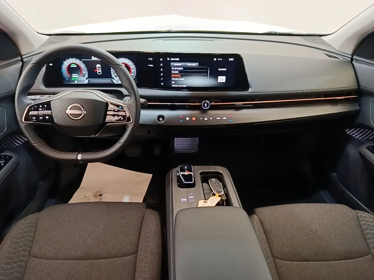 Vue intérieure avant du Nissan Ariya 63kWh noir, avec tableau de bord numérique et volant multifonctions cuir.