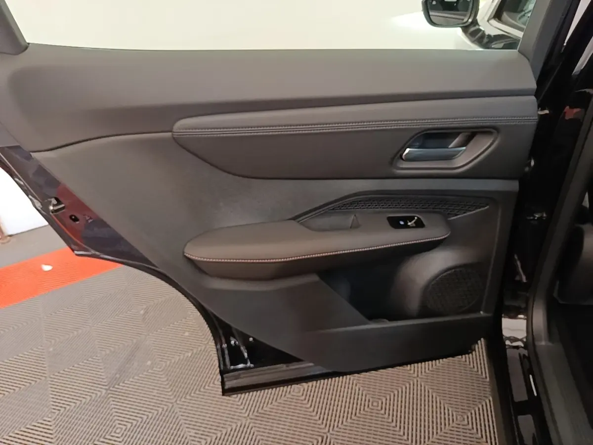 Vue rapprochée de la porte arrière droite noire du Nissan Ariya 2026 avec accoudoir en cuir et commande de vitre.