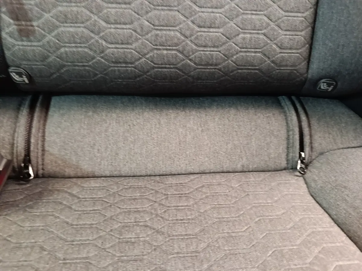 Détail de la banquette arrière grise du Nissan Ariya 63kWh 218ch Engage, tissu à motifs hexagonaux et attaches Isofix visibles.