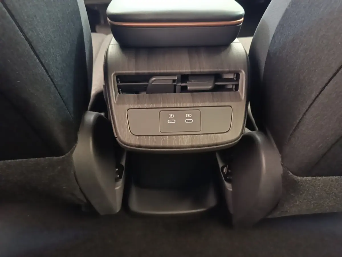 Vue rapprochée de la console arrière du Nissan Ariya noir avec prises USB-C et sortie d'air pour les passagers arrière.