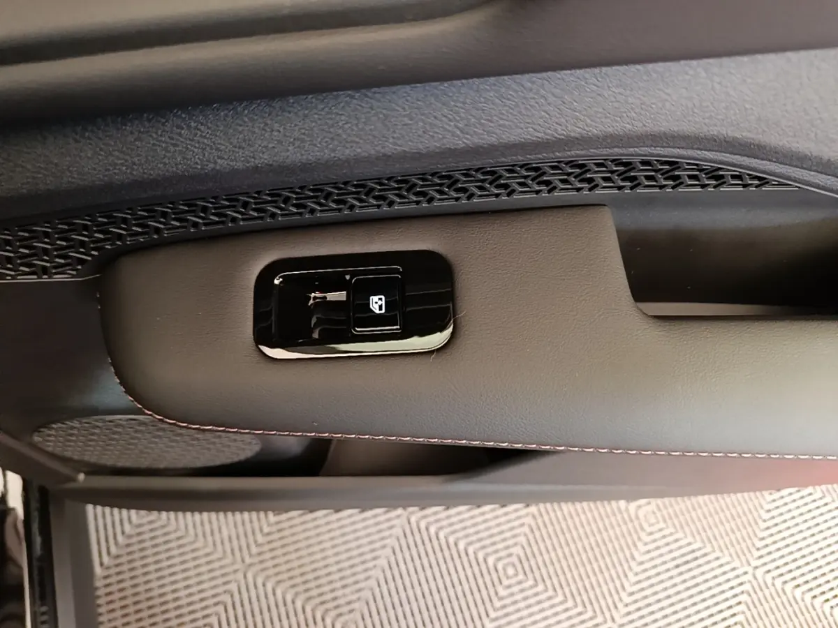 Détail de la commande de lève-vitre sur la porte intérieure côté conducteur du Nissan Ariya noir 2026.
