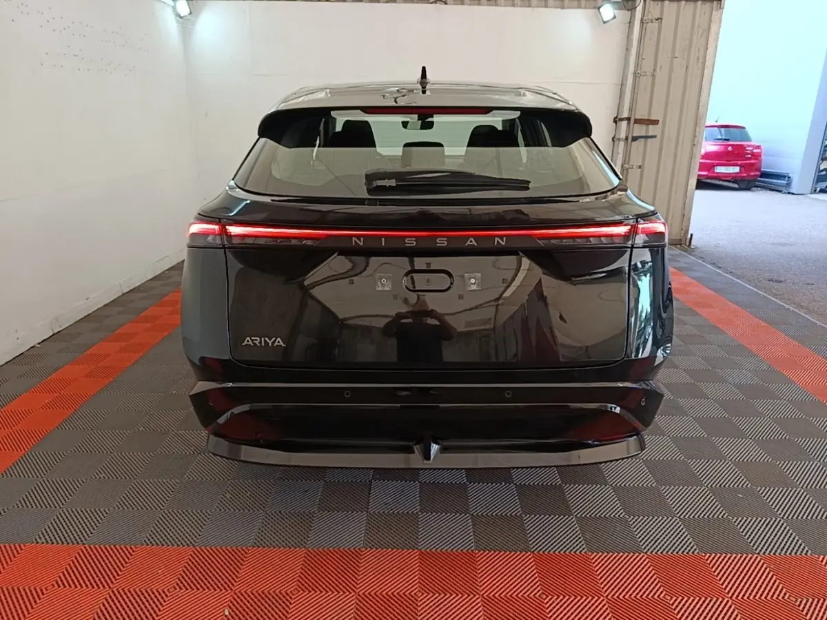 Vue arrière d'un Nissan Ariya noir 2026 avec feux arrière LED continus et logo Nissan lumineux.