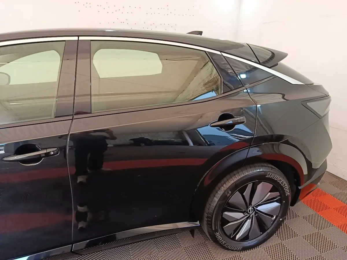 Vue latérale côté droit du Nissan Ariya noir 63kWh 218ch Engage, mettant en valeur la roue arrière et la ligne de toit dynamique.