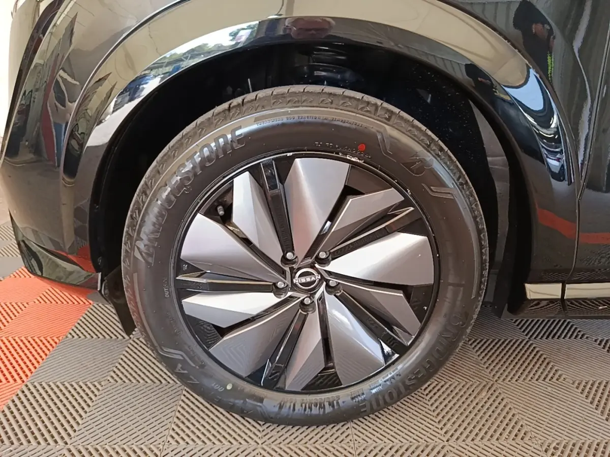 Gros plan sur la roue avant droite noire du Nissan Ariya 63kWh 218ch Engage avec jante design bicolore.