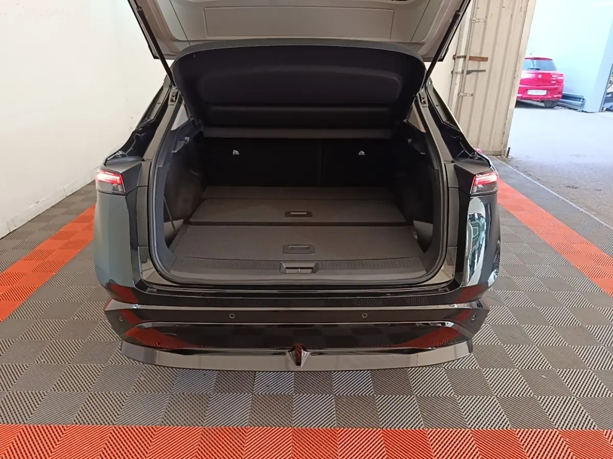 Vue arrière du coffre ouvert du Nissan Ariya noir 63kWh 218ch Engage, montrant l'espace de chargement plat.