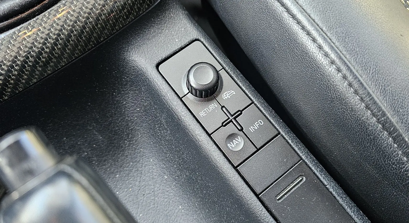 Gros plan sur la console centrale noire de l'Audi RS4 Avant B5, mettant en valeur les boutons de navigation et retour.