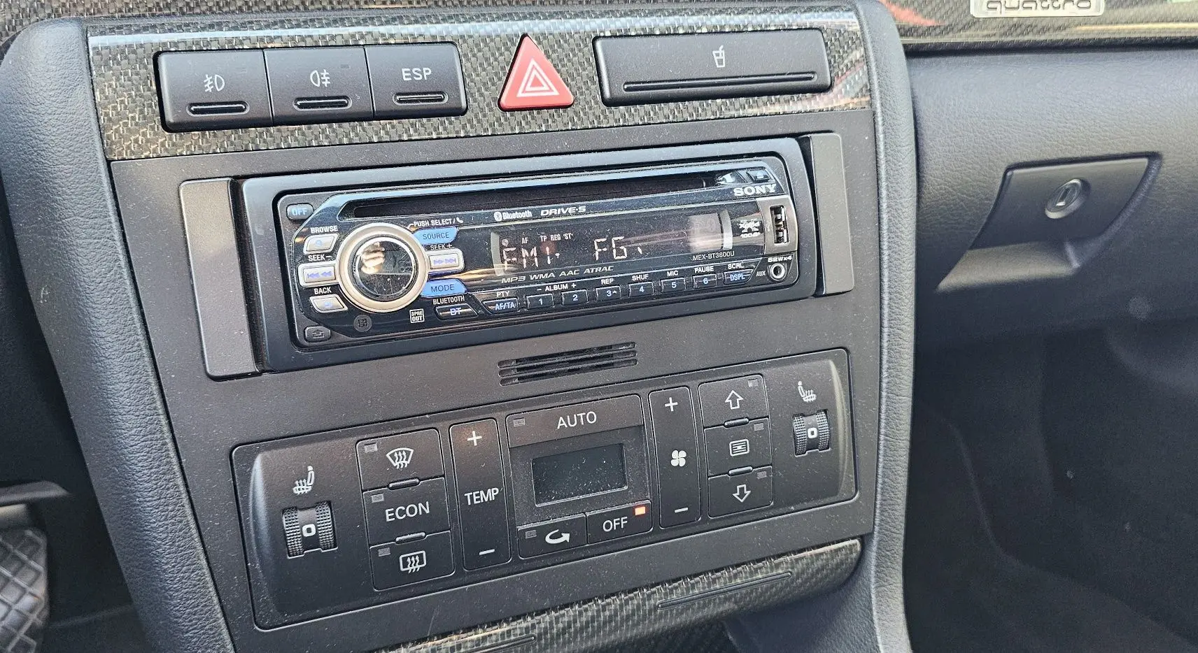 Gros plan sur la console centrale noire de l'Audi RS4 Avant B5, montrant autoradio Sony et commandes de climatisation.