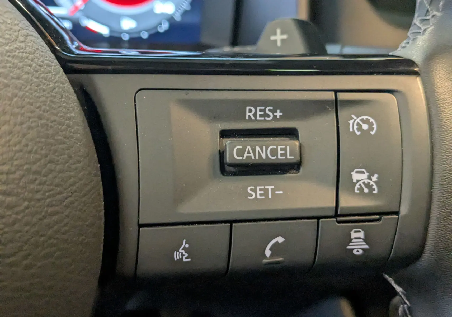 Gros plan sur les commandes du régulateur de vitesse au volant du Nissan Qashqai blanc 2024.