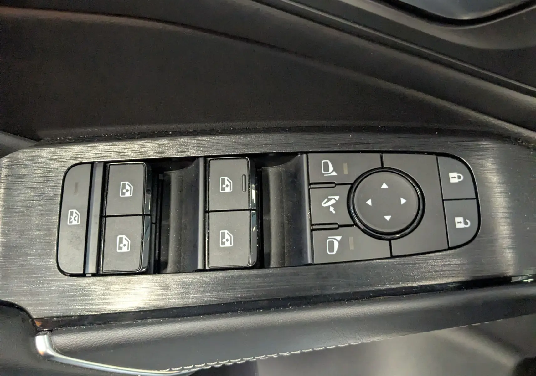 Gros plan sur les commandes de lève-vitres et réglages des rétroviseurs côté conducteur du Nissan Qashqai blanc 2024.