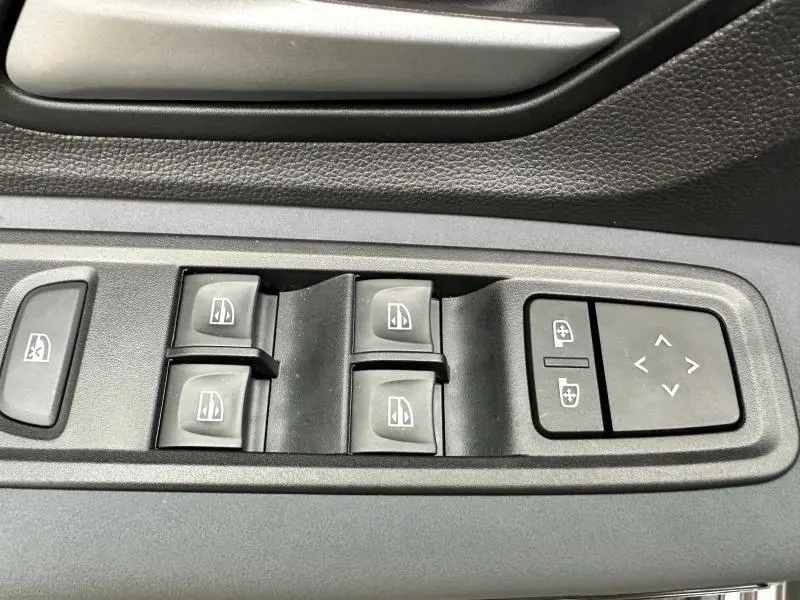 Gros plan sur les commandes des vitres électriques et des rétroviseurs sur la porte côté conducteur du Dacia Jogger 2024.