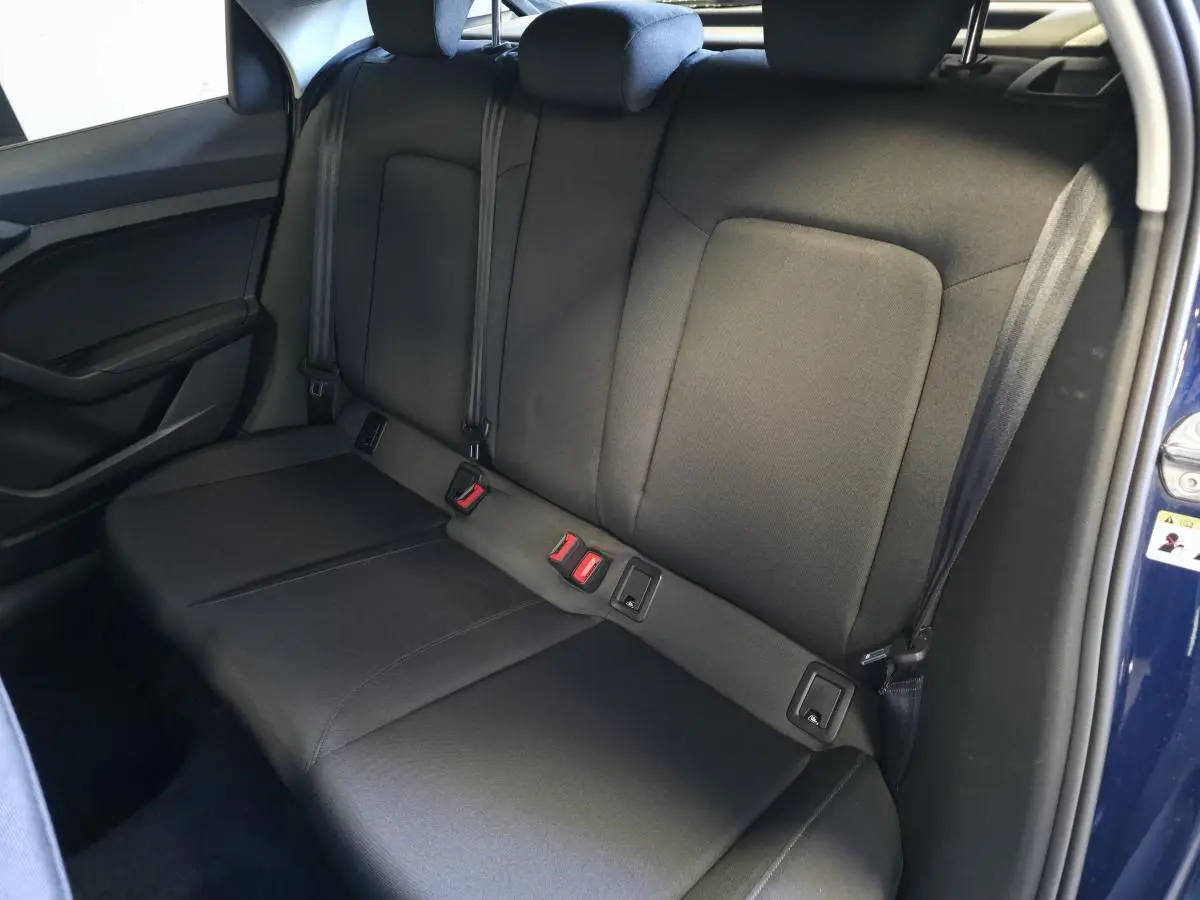 Vue intérieure de la banquette arrière en tissu noir de l'Audi A1 Sportback 2024, porte ouverte côté droit.