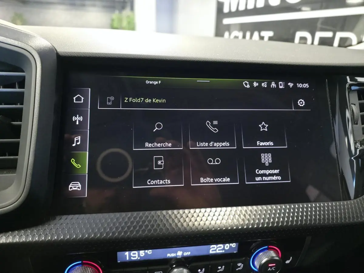 Écran tactile central de l’Audi A1 Sportback 2024 avec interface téléphone, entouré de décorations noires à motifs polygonaux.