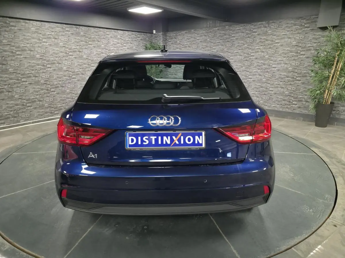 Vue arrière d'une Audi A1 Sportback 2024 bleu métallisé avec feux LED et logo distinctif sur fond intérieur gris.