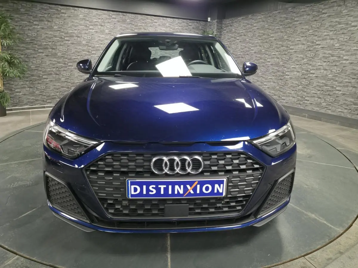 Vue frontale d'une Audi A1 Sportback 2024 bleu métallisé avec calandre noire et phares LED anguleux.