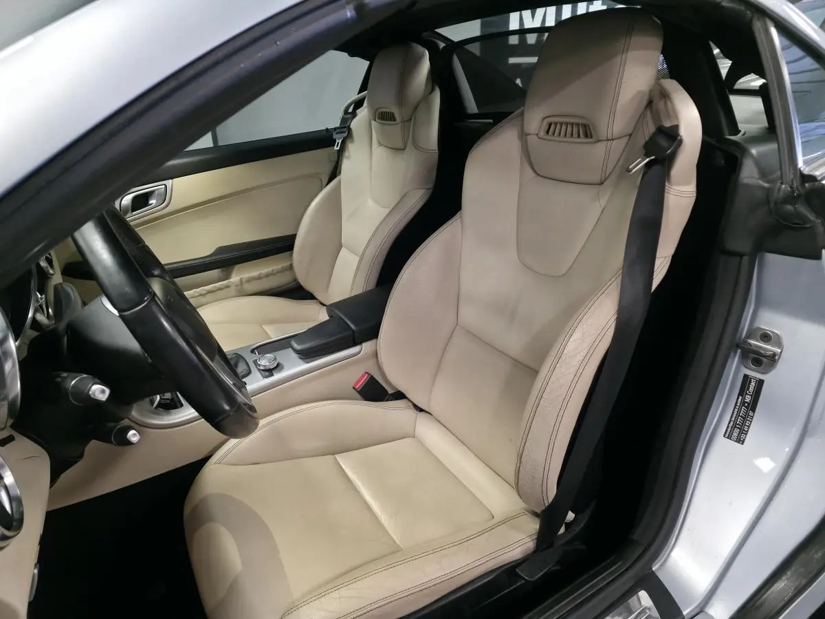 Intérieur de la Mercedes SLK 250 CDI gris, vue côté conducteur sur les sièges sport cuir beige et console centrale.