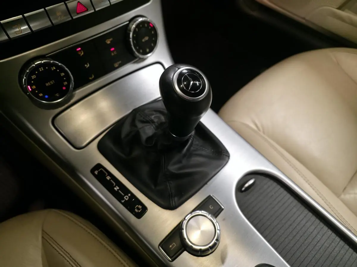 Vue rapprochée de la console centrale d'une Mercedes SLK 250 CDI gris, avec levier de vitesses cuir et sellerie beige.