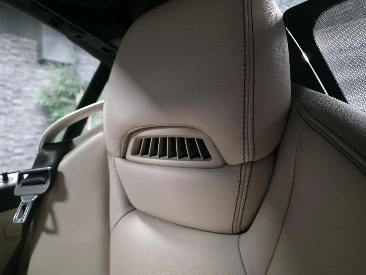 Gros plan sur l'appuie-tête en cuir beige avec sortie d'air intégrée du siège avant d'une Mercedes SLK gris 2012.