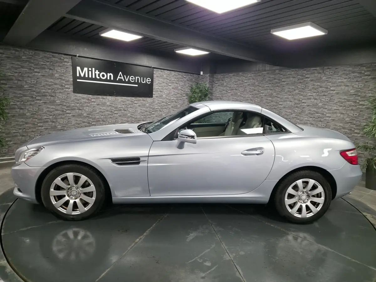 Profil côté gauche d'une Mercedes SLK 250 CDI gris métallisé avec toit rigide et sellerie cuir beige visible.