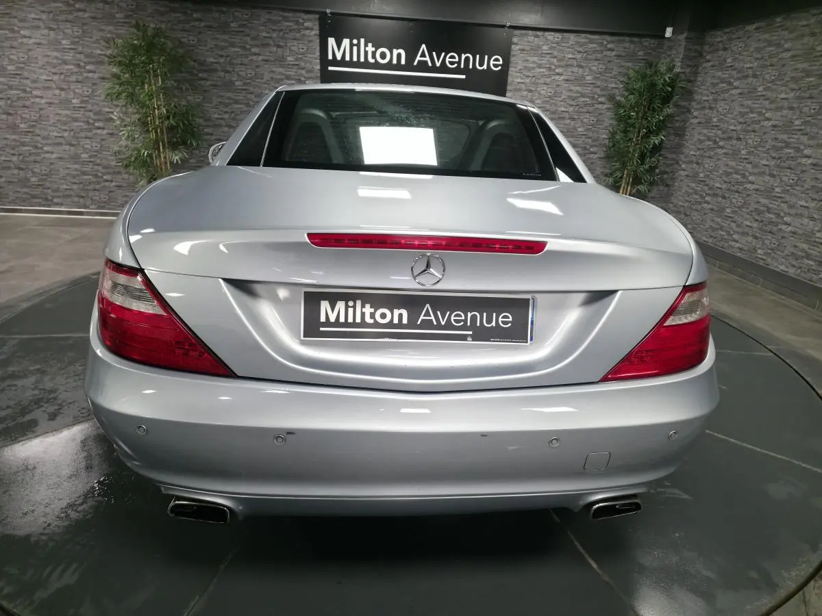 Vue arrière d'une Mercedes SLK gris métallisé avec feux rouges et double sortie d'échappement chromée.