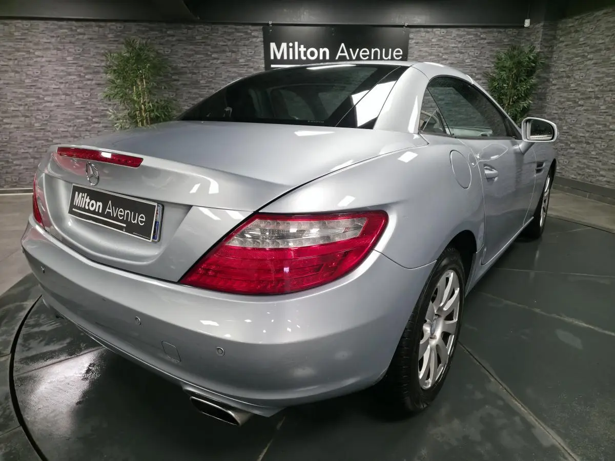 Vue 3/4 arrière droite d'une Mercedes SLK gris métallisé avec feux arrière LED et échappement double chromé.