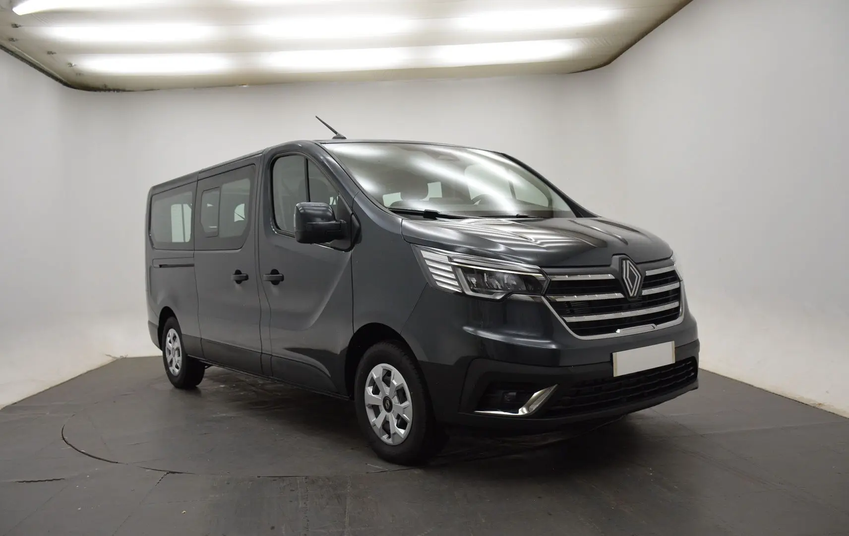 Renault Trafic Combi gris comète en 3/4 avant droit, fourgon 9 places avec calandre chromée et phares LED.