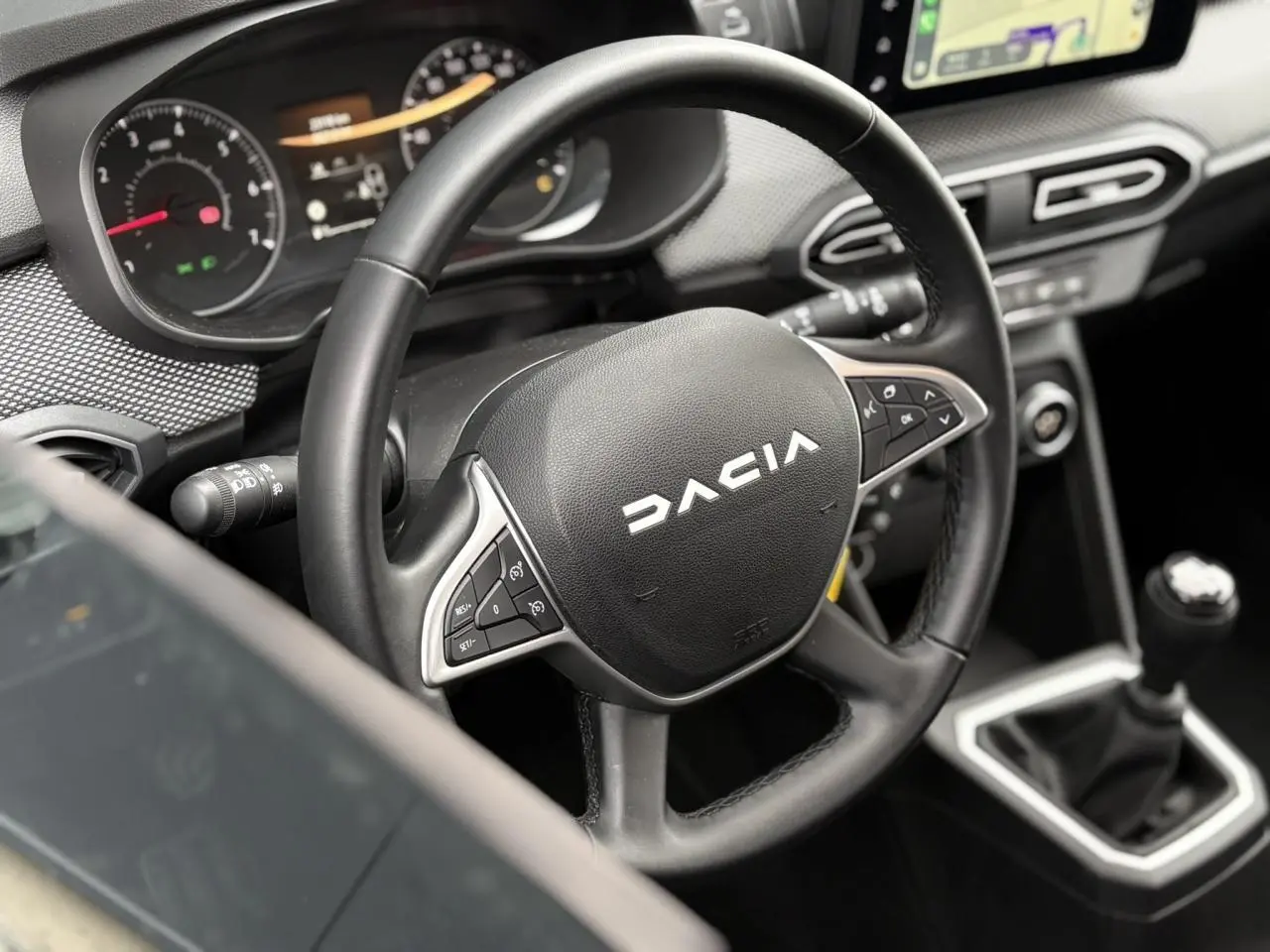 Vue rapprochée de l'intérieur du Dacia Jogger 2025, volant noir avec commandes et levier de vitesses manuel visible.