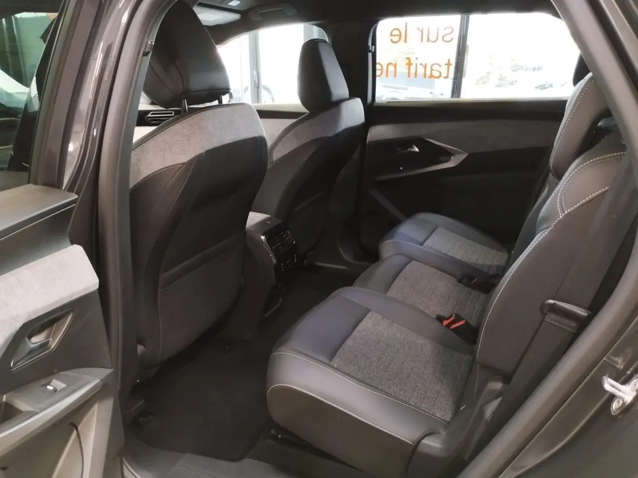 Vue côté droit de l'habitacle arrière du Peugeot 5008 gris titanium avec sellerie tissu et cuir gris foncé.