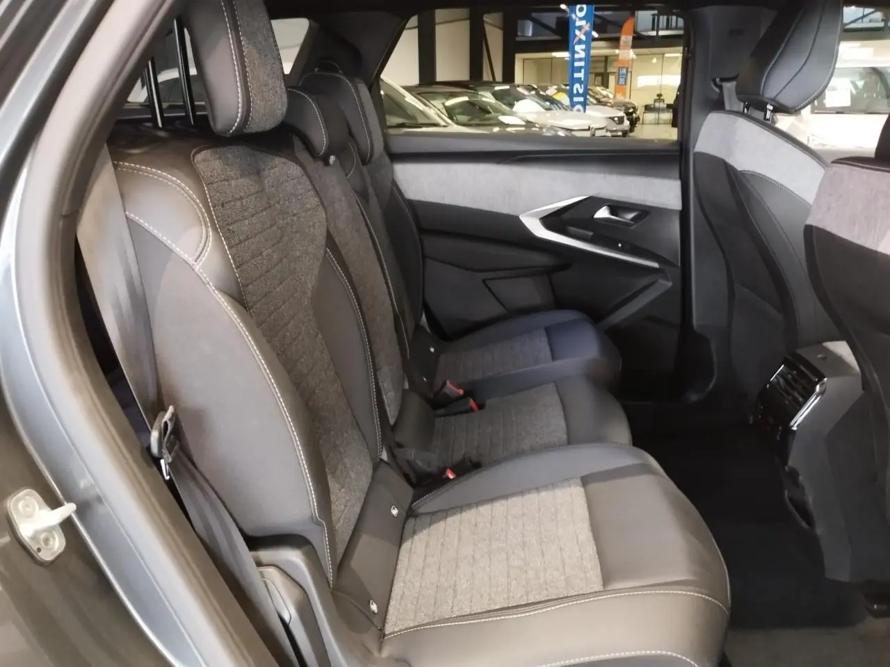 Vue côté gauche des sièges arrière gris tissu et cuir du Peugeot 5008 2025 avec détails couture blanche et habillage de porte assorti.