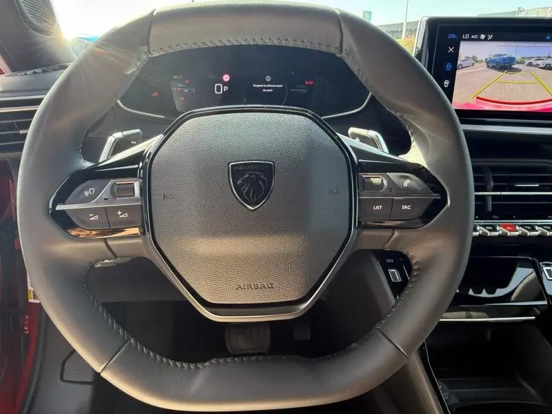 Vue rapprochée du volant cuir noir du Peugeot 2008 1.2 Hybrid 145ch Allure 2025 avec écran de recul et tableau de bord digital.