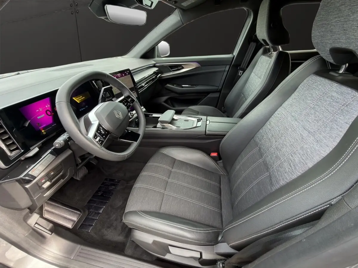 Vue intérieure côté conducteur du Renault Austral gris foncé, avec sièges tissu et cuir, volant multifonctions et écran tactile central.