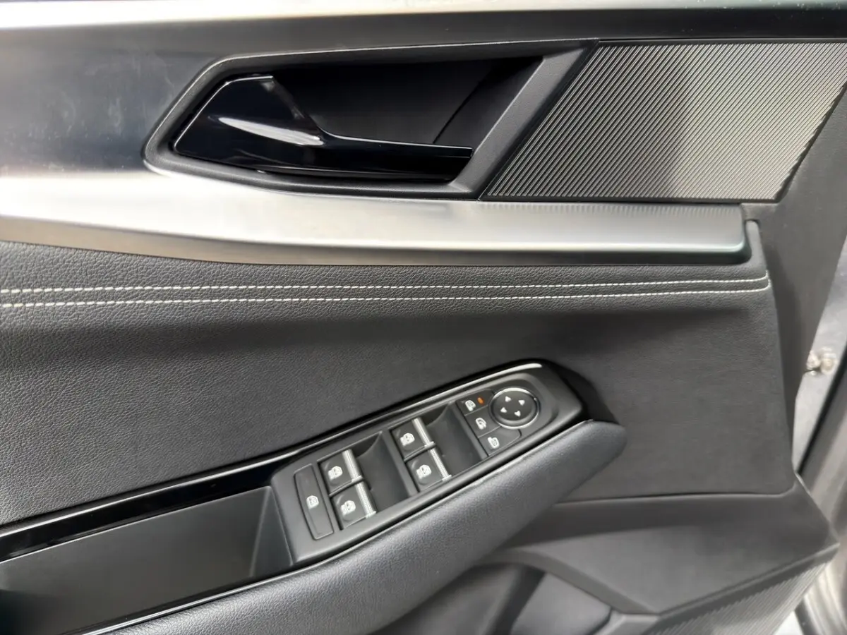 Gros plan sur la porte avant gauche gris foncé du Renault Austral avec commandes électriques des vitres et rétroviseurs.