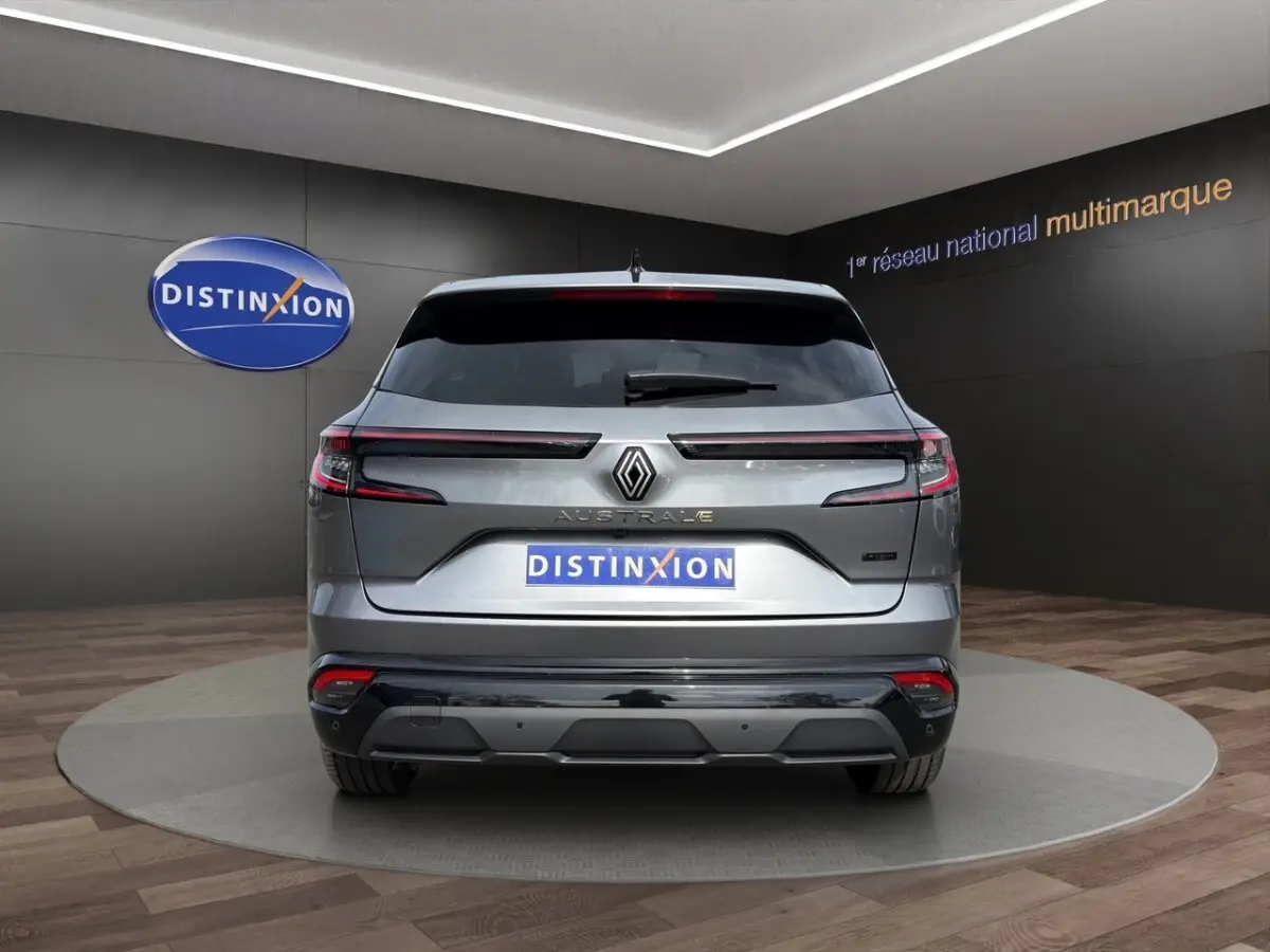 Vue arrière d'un Renault Austral gris foncé avec feux LED horizontaux et logo central lumineux dans un showroom.