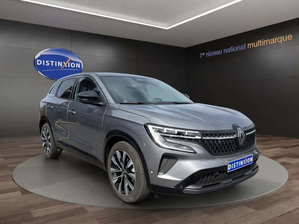 Renault Austral Techno E-Tech gris foncé en 3/4 avant droit, avec calandre noire et jantes alliage distinctives.