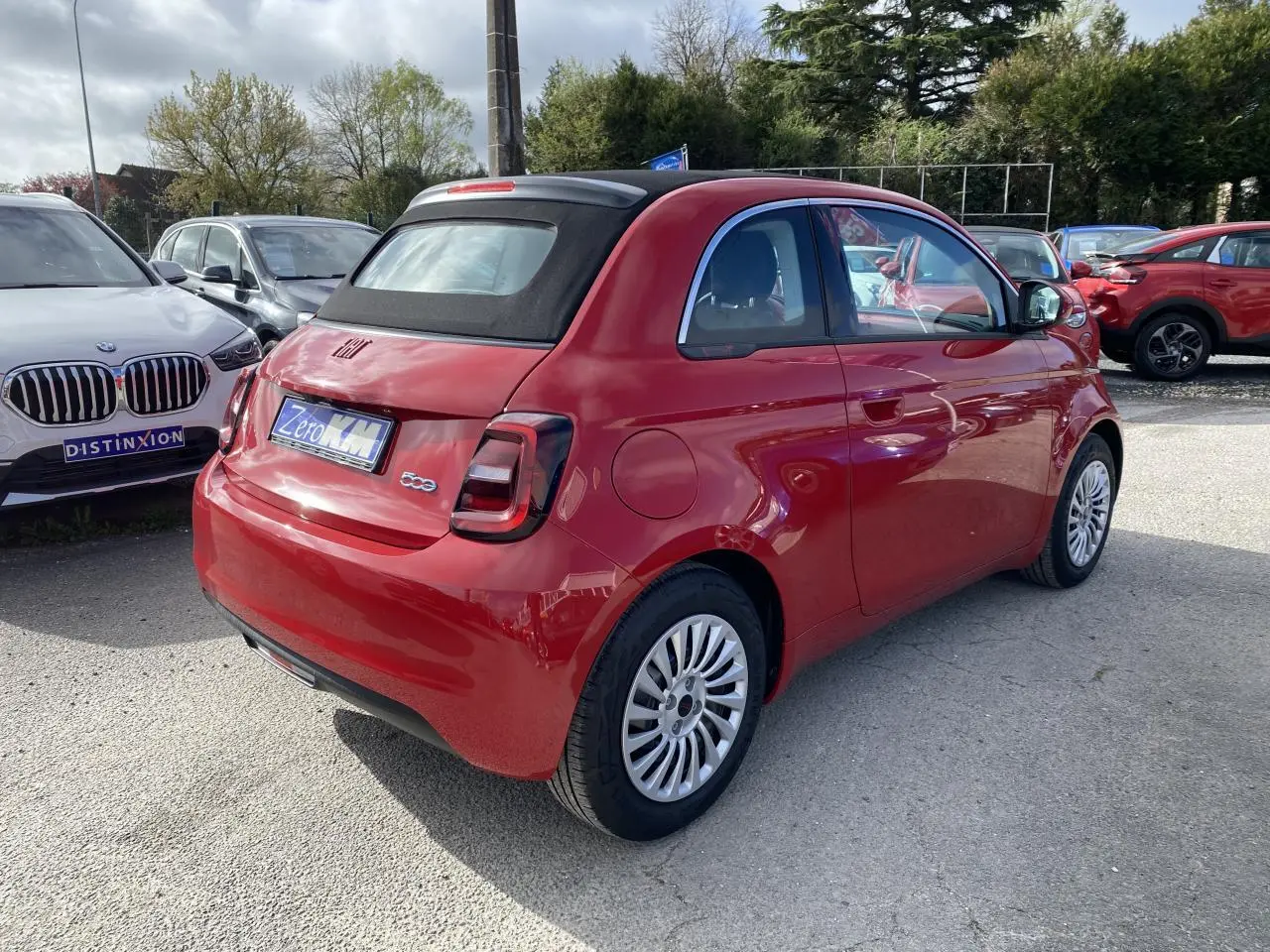 Fiat 500 Cabriolet électrique rouge vue 3/4 arrière droit avec toit souple noir et jantes alliage 16 pouces.