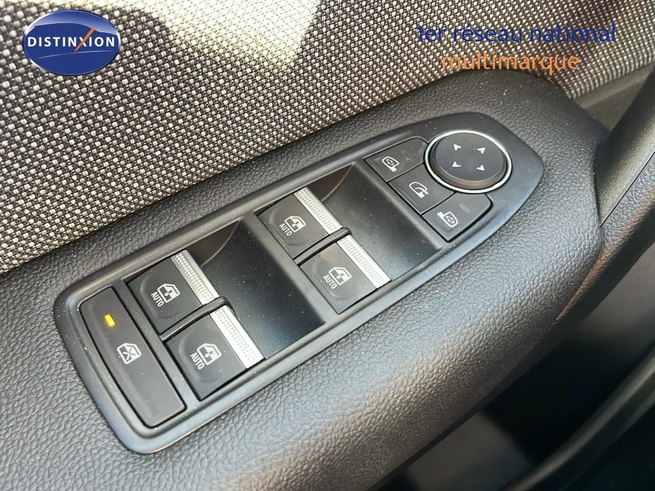 Gros plan sur les commandes des vitres électriques et rétroviseurs du côté gauche d'un Renault Captur gris Rafale métal toit noir.