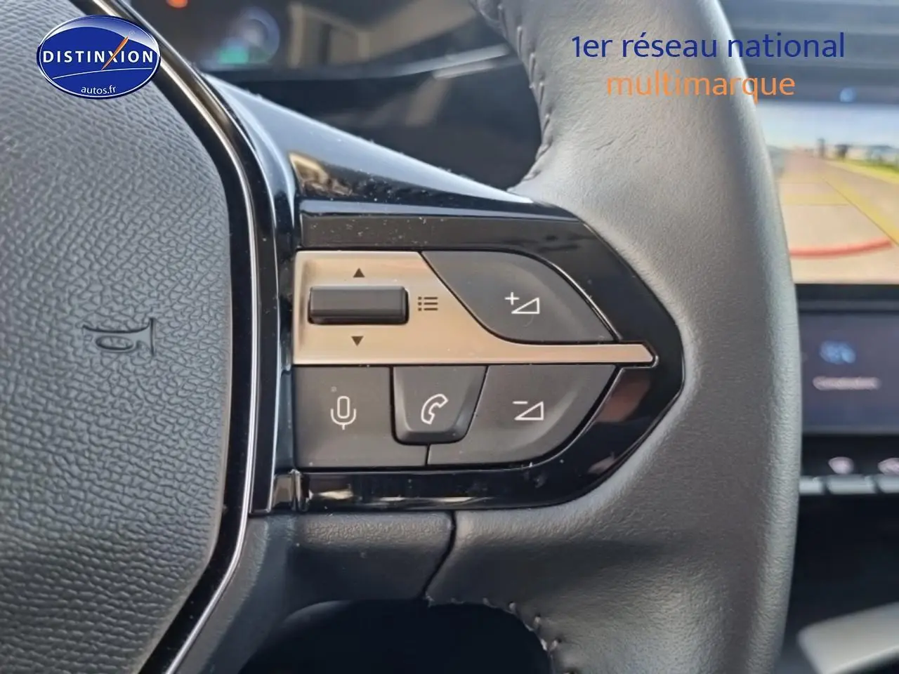 Gros plan sur les commandes du volant cuir noir de la Peugeot 408 Hybrid 145 allure e-dcs6, avec écran tactile en arrière-plan.