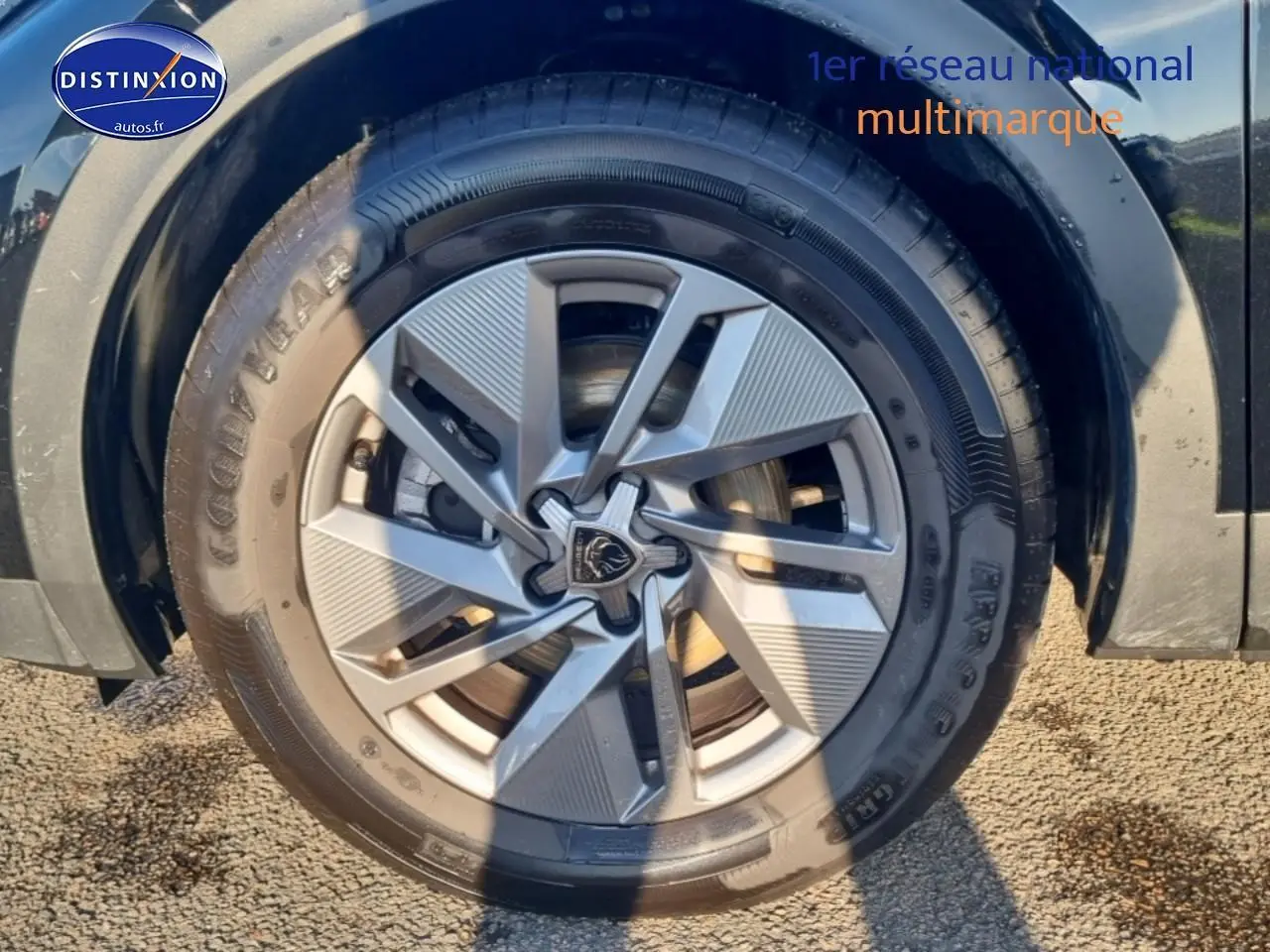 Gros plan sur la jante alu gris clair et le pneu Goodyear du côté avant droit d'une Peugeot 408 noire.