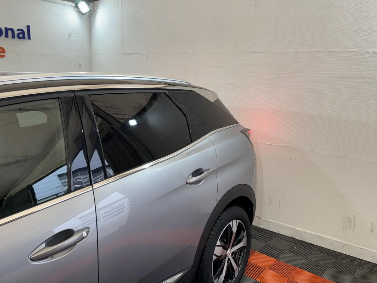 Vue côté droit arrière d'un Peugeot 3008 gris clair avec vitres teintées et jantes alliage noires et chromées.