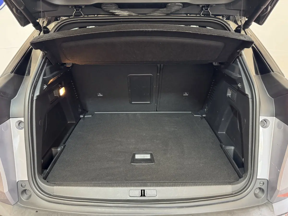 Coffre ouvert d’un Peugeot 3008 gris clair, vue arrière montrant l’espace de rangement vide et la tablette de couverture.
