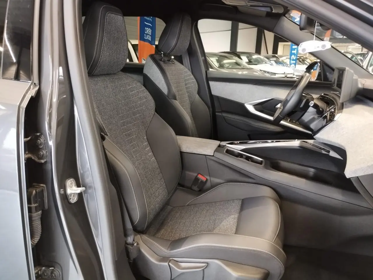 Vue intérieure côté gauche du Peugeot 5008 gris titanium, mettant en valeur les sièges tissu et cuir avec surpiqûres contrastées.