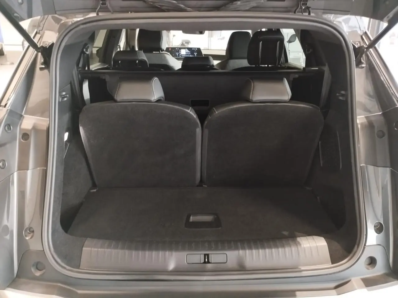 Coffre ouvert vue arrière du Peugeot 5008 gris titanium avec banquette rang 3 relevée et intérieur sombre.