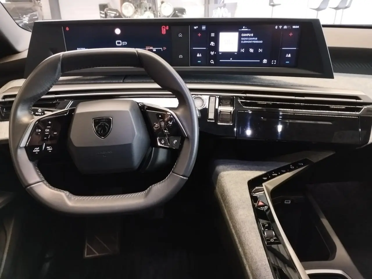 Vue intérieure centrée sur le volant compact et le tableau de bord numérique du Peugeot 5008 gris titanium 2025.