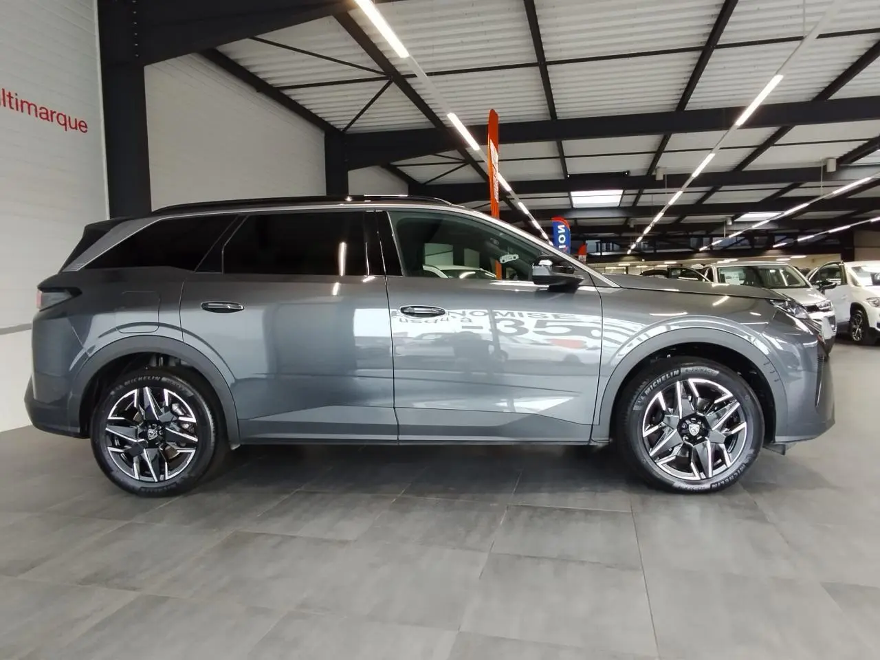 Peugeot 5008 gris titanium vue de profil côté gauche en intérieur avec jantes alliage 19 pouces.