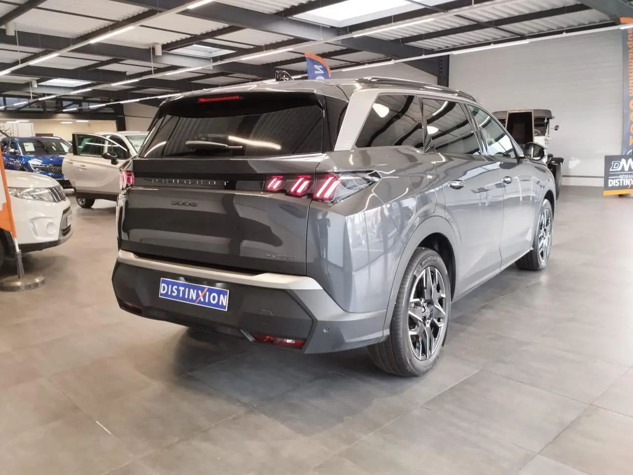 Vue 3/4 arrière droite d'un Peugeot 5008 gris titanium avec feux arrière LED 3 griffes et jantes alliage 19 pouces.