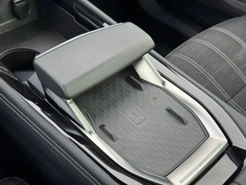 Gros plan sur la console centrale noire du Renault Austral 2025 avec repose-bras et surface de charge sans fil.