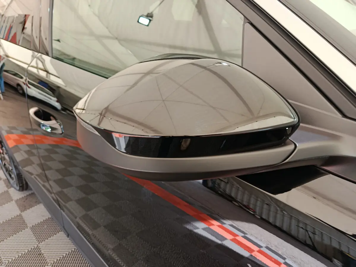 Rétroviseur côté gauche noir brillant d’un Peugeot 3008 1.2 Hybrid 145 GT, reflet du plafond intérieur visible.