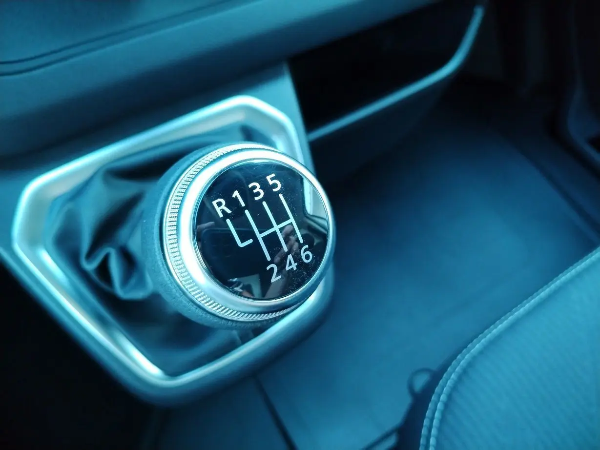 Gros plan sur le levier de vitesse manuel noir et chrome du Nissan Primastar 2025 à intérieur sombre.