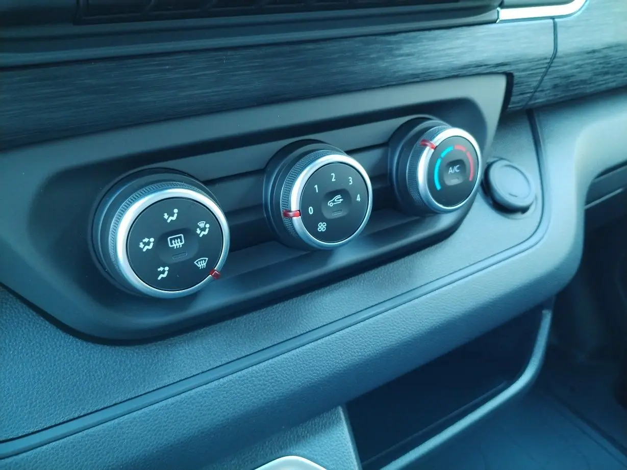 Gros plan sur les commandes de climatisation noires et argent du tableau de bord du Nissan Primastar blanc 2025.