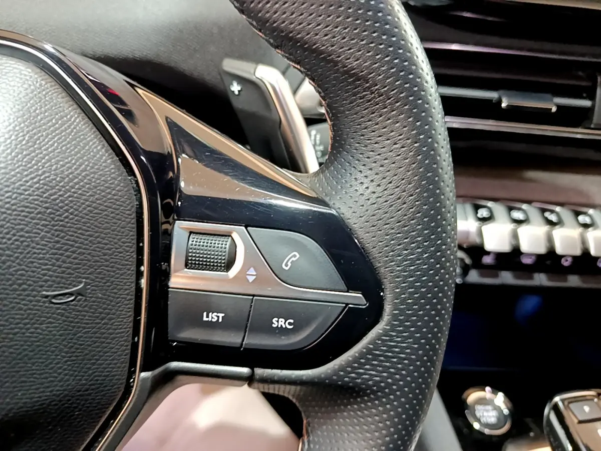 Gros plan sur le volant cuir noir du Peugeot 3008 2023 avec commandes audio et téléphone intégrées.