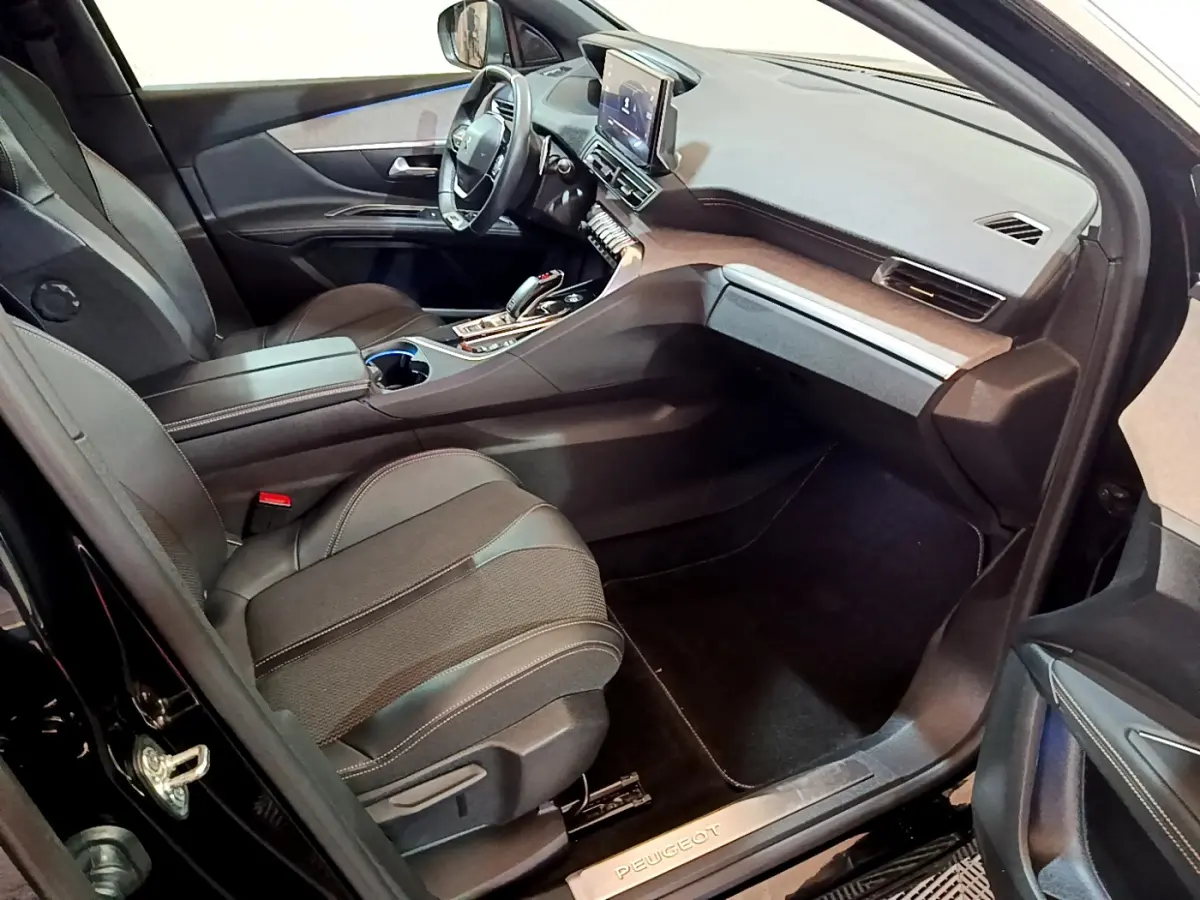 Vue intérieure côté passager du Peugeot 3008 GT 2023 noir, avec tableau de bord moderne et sièges en tissu noir.